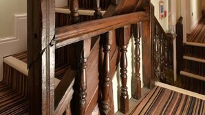A wooden staircase with a handrail and a striped carpet. - The Woolly Sheep Inn (Skipton)