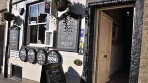 A building with a black and white facade, a door, and a signboard with room numbers. - The Woolly Sheep Inn (Skipton)
