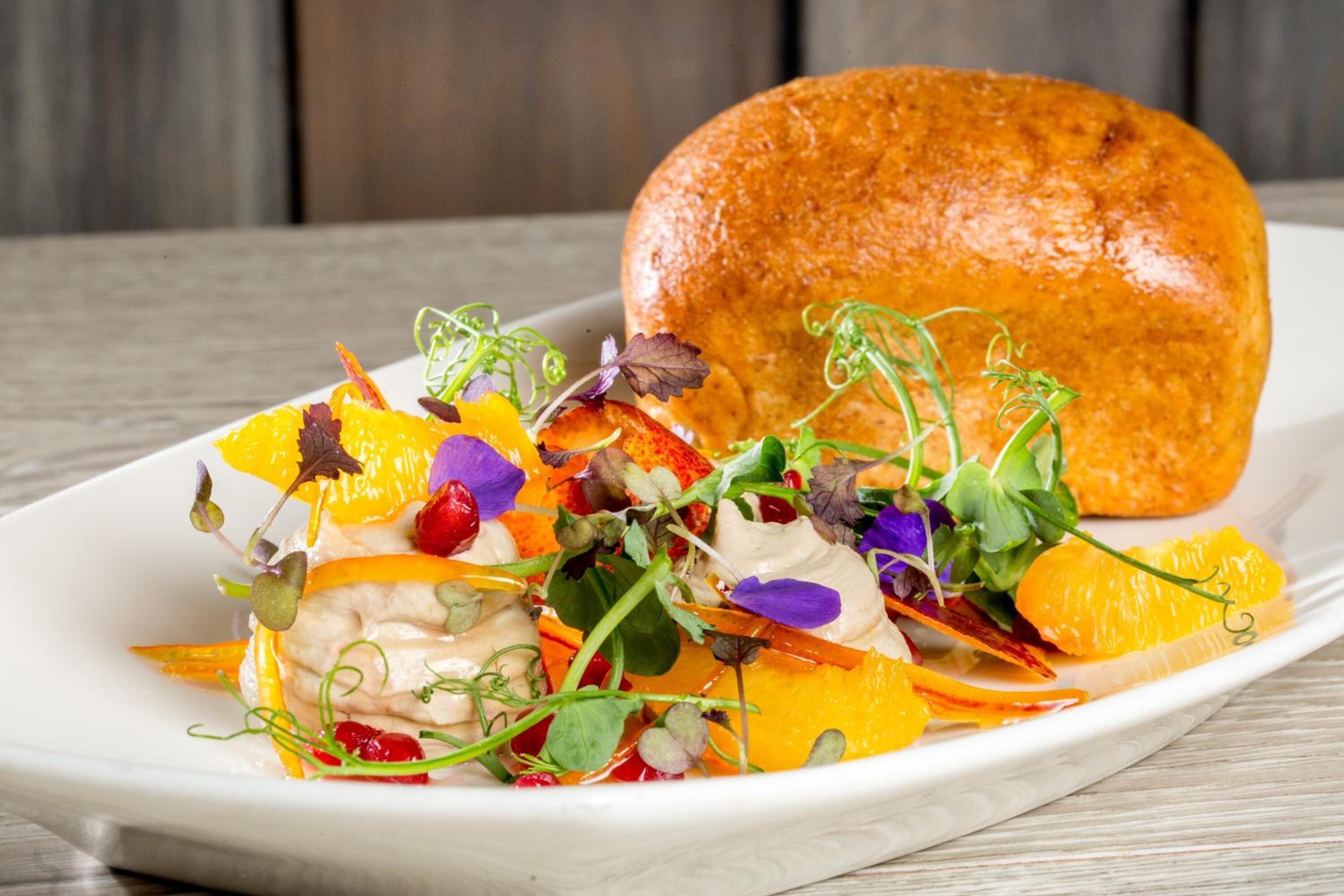 A white plate with a salad and a loaf of bread.