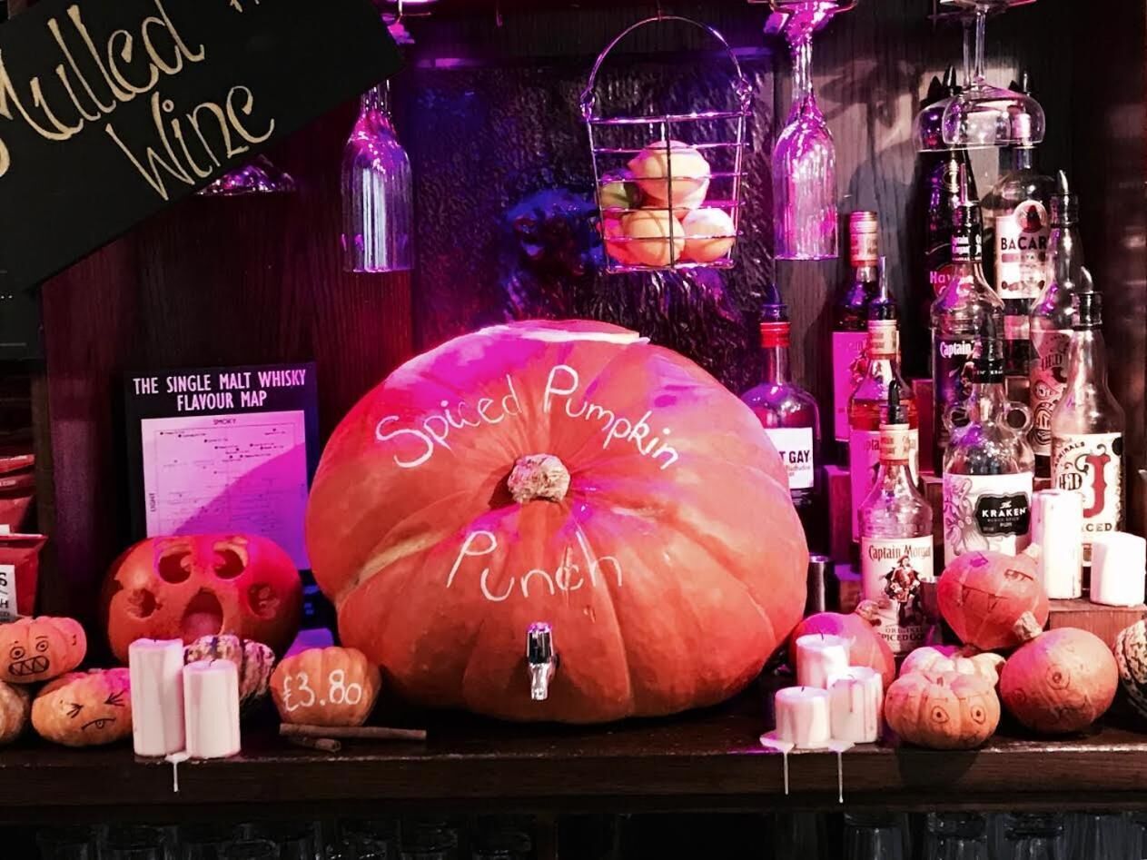 A display of pumpkins and alcohol bottles, including a large Spiced Pumpkin Punch priced at £3.80.