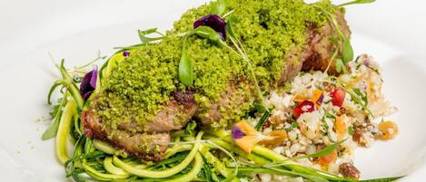 Un plato de comida con cobertura verde, verduras y un acompañamiento a base de cereales.