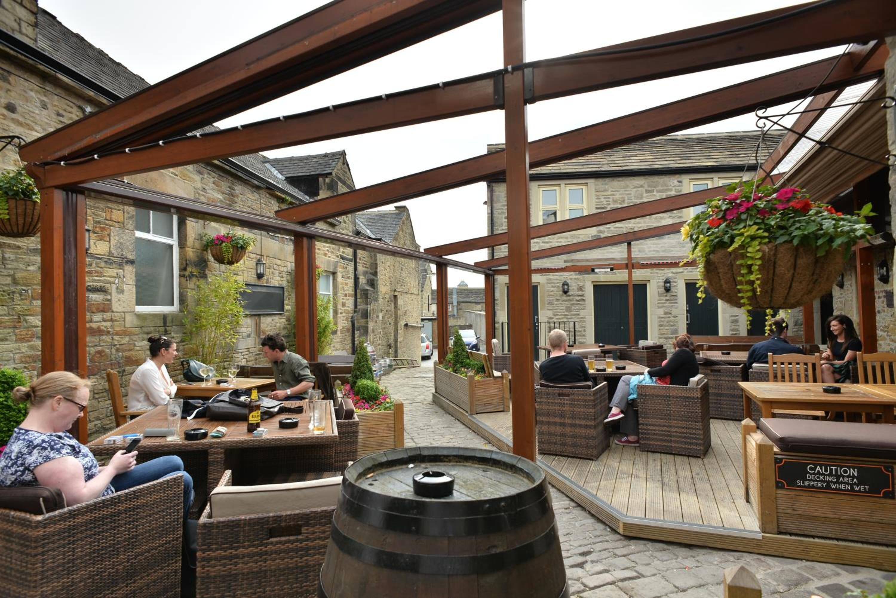 Ein Patio im Freien mit Korbmöbeln, Steinwänden und hängenden Blumenkörben.