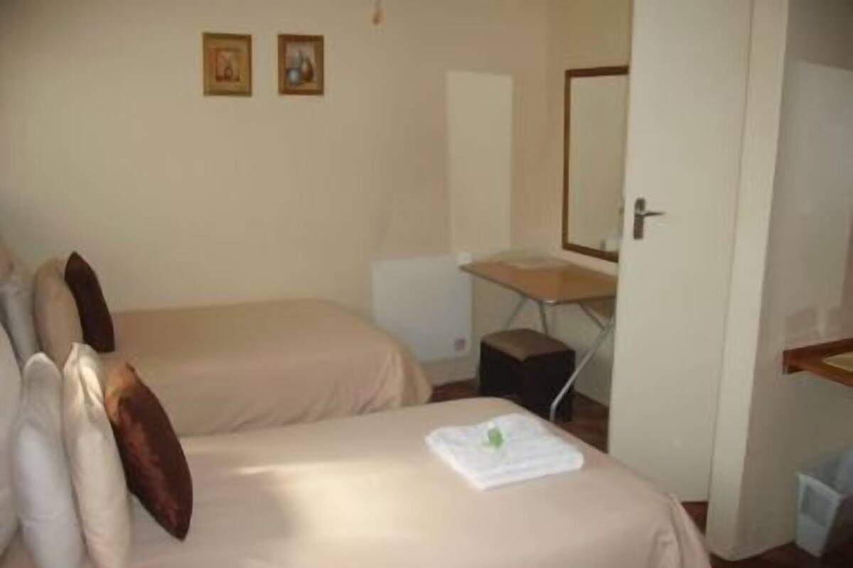 Una habitación de hotel con dos camas, un escritorio, una silla, un espejo y una puerta.