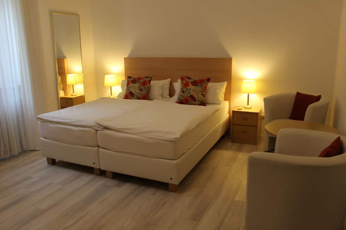 A hotel room with a large bed, two bedside tables with lamps, a chair, and a mirror on the wall.