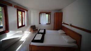 A bedroom with a single bed, a wooden headboard, a nightstand, a chair, and a window with curtains. - Altin Camp & Park Hotel (Burhaniye)