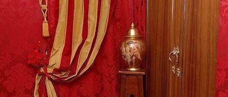 A room with red walls, a wooden wardrobe, and a small table with a decorative item.
