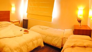 Una habitación de hotel con dos camas, cabeceros de madera, mesitas de noche y lámparas de pared.