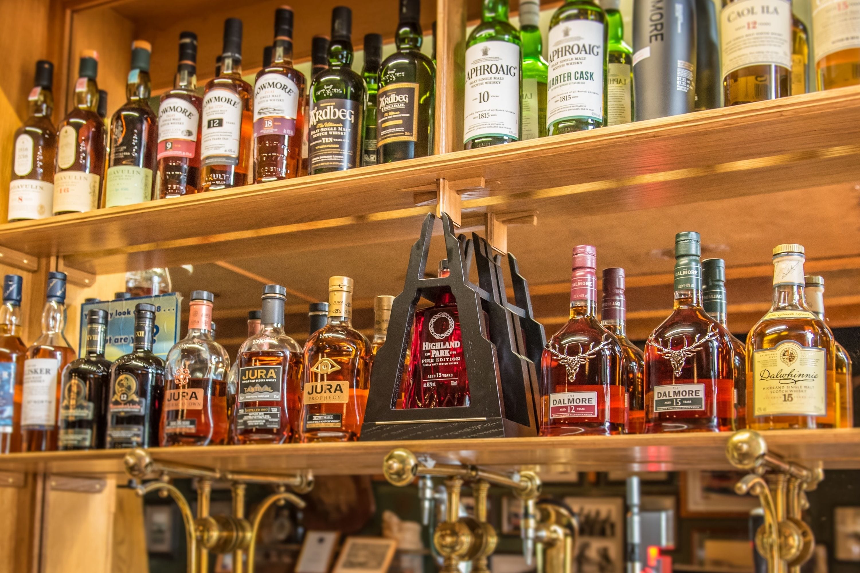 A liquor store shelf with various bottles of alcohol, including brands like Jura and Dalmore.