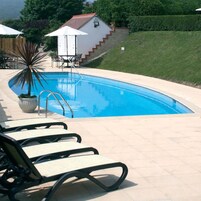A swimming pool with lounge chairs and a small building with a red roof.