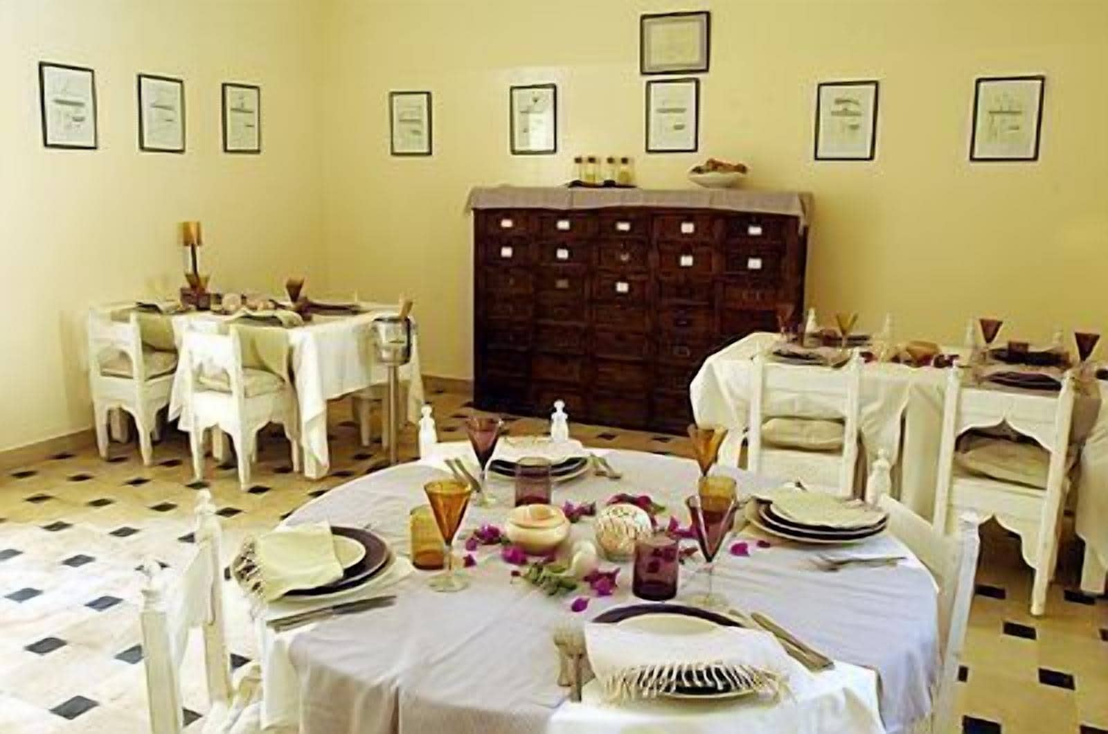 A dining area with round tables set for a meal, white chairs, and a patterned floor.