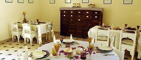 A dining area with round tables set for a meal, white chairs, and a patterned floor.