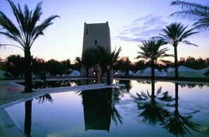 Relax by the serene pool surrounded by palm trees and a tranquil atmosphere.