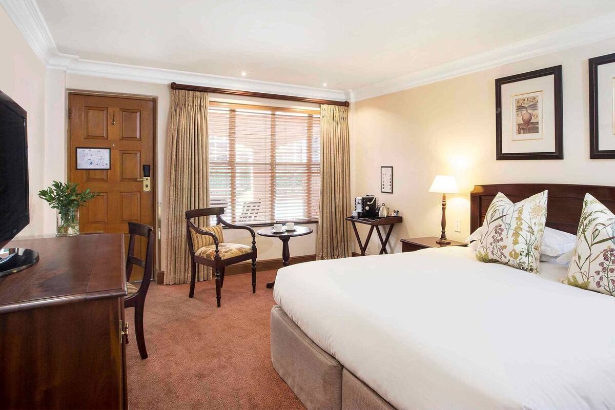 Een hotelkamer met een bed, een bureau, een stoel, een tafel, een lamp en een televisie.