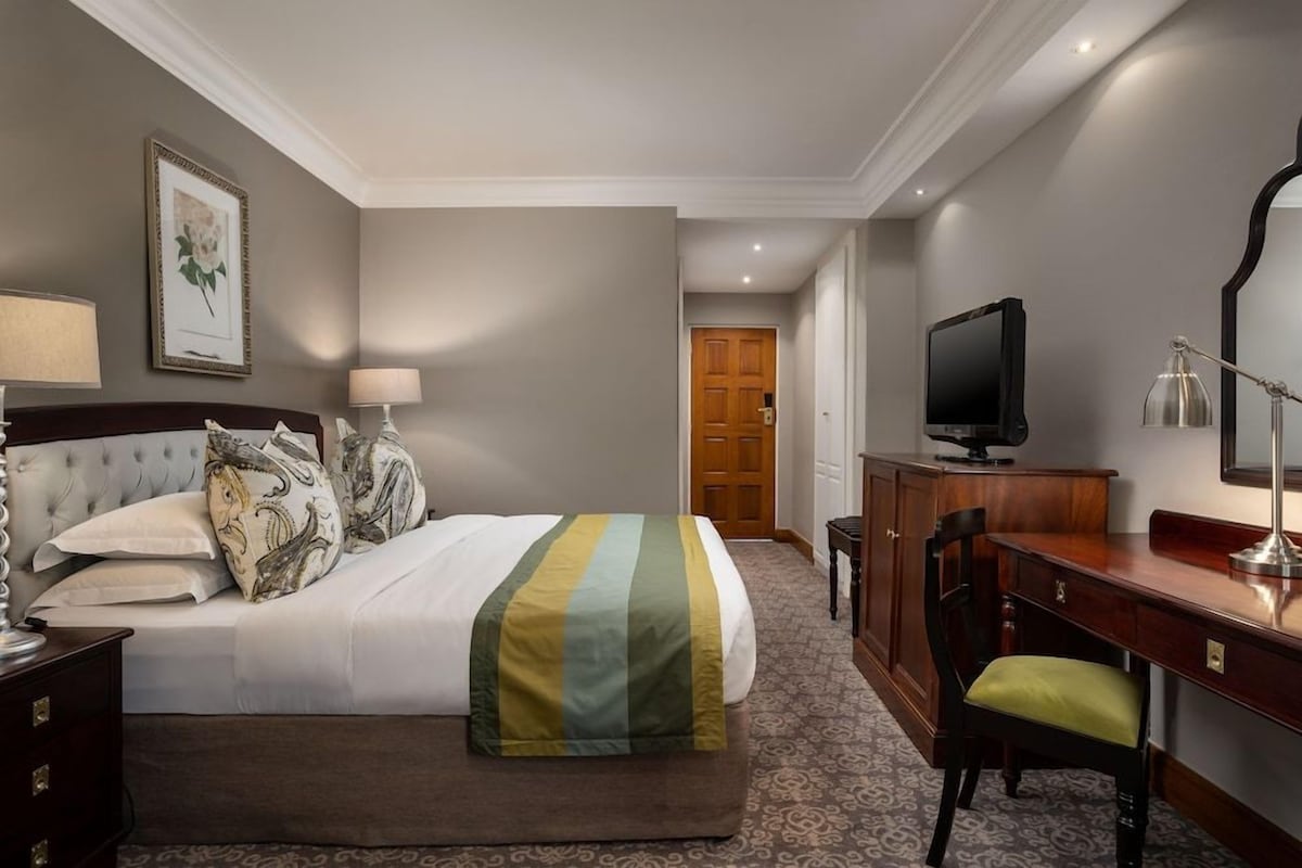 Une chambre d’hôtel équipée d’un lit, d’un bureau, d’une télévision et d’une chaise.