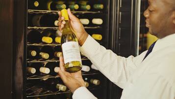 A person selecting a bottle from a wine rack.