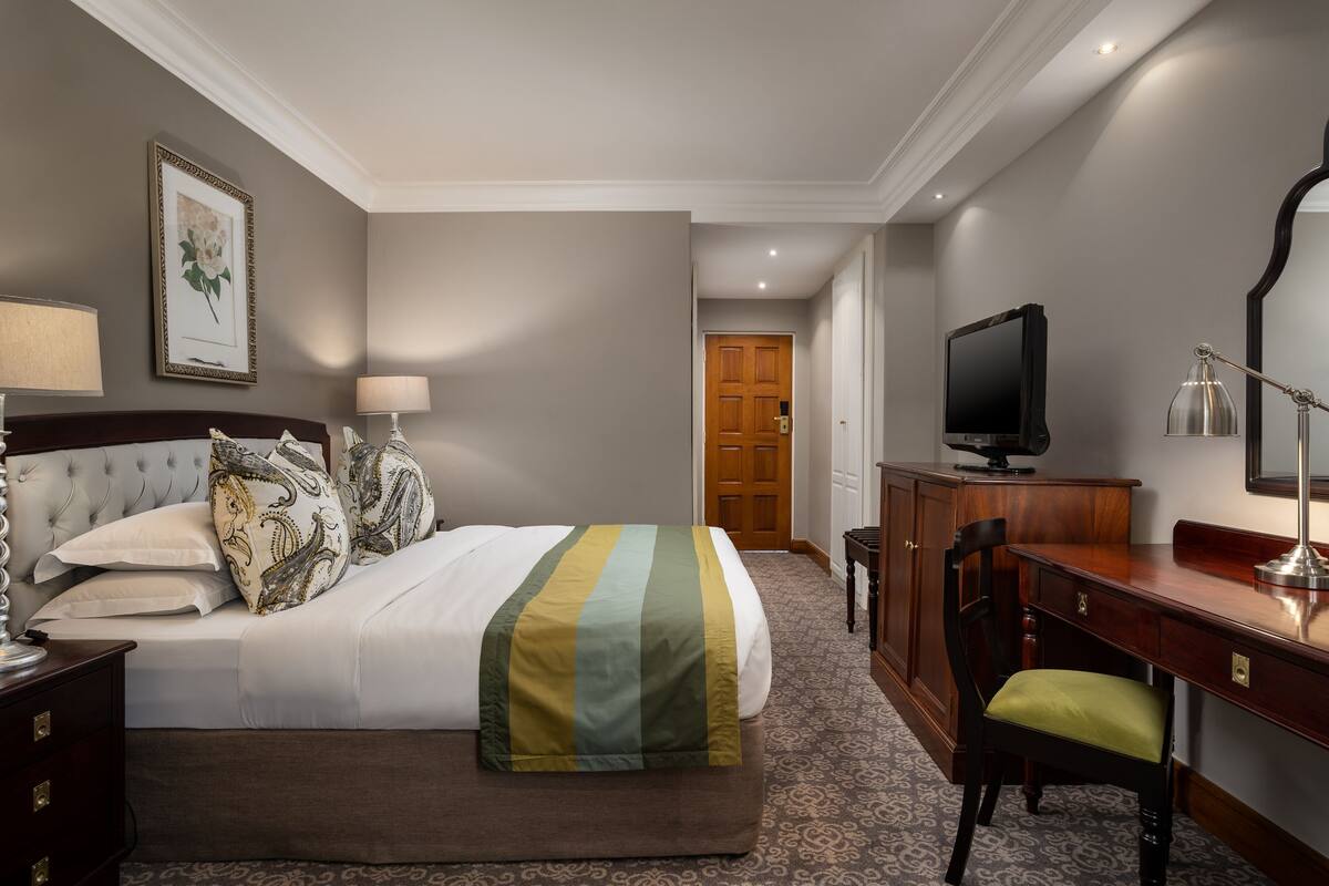 Een hotelkamer met een bed, een bureau, een televisie en een stoel.