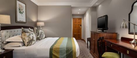 A hotel room with a bed, a desk, a television, and a chair.
