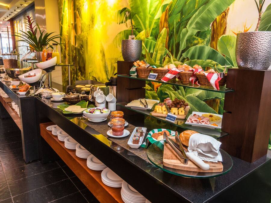 Een buffet met diverse gerechten en een groene plantenwand op de achtergrond.