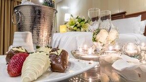 Een desserttafel met chocoladegedroogde aardbeien, een wit chocoladeglans-gebakje en een champagnefles in een metalen emmer.