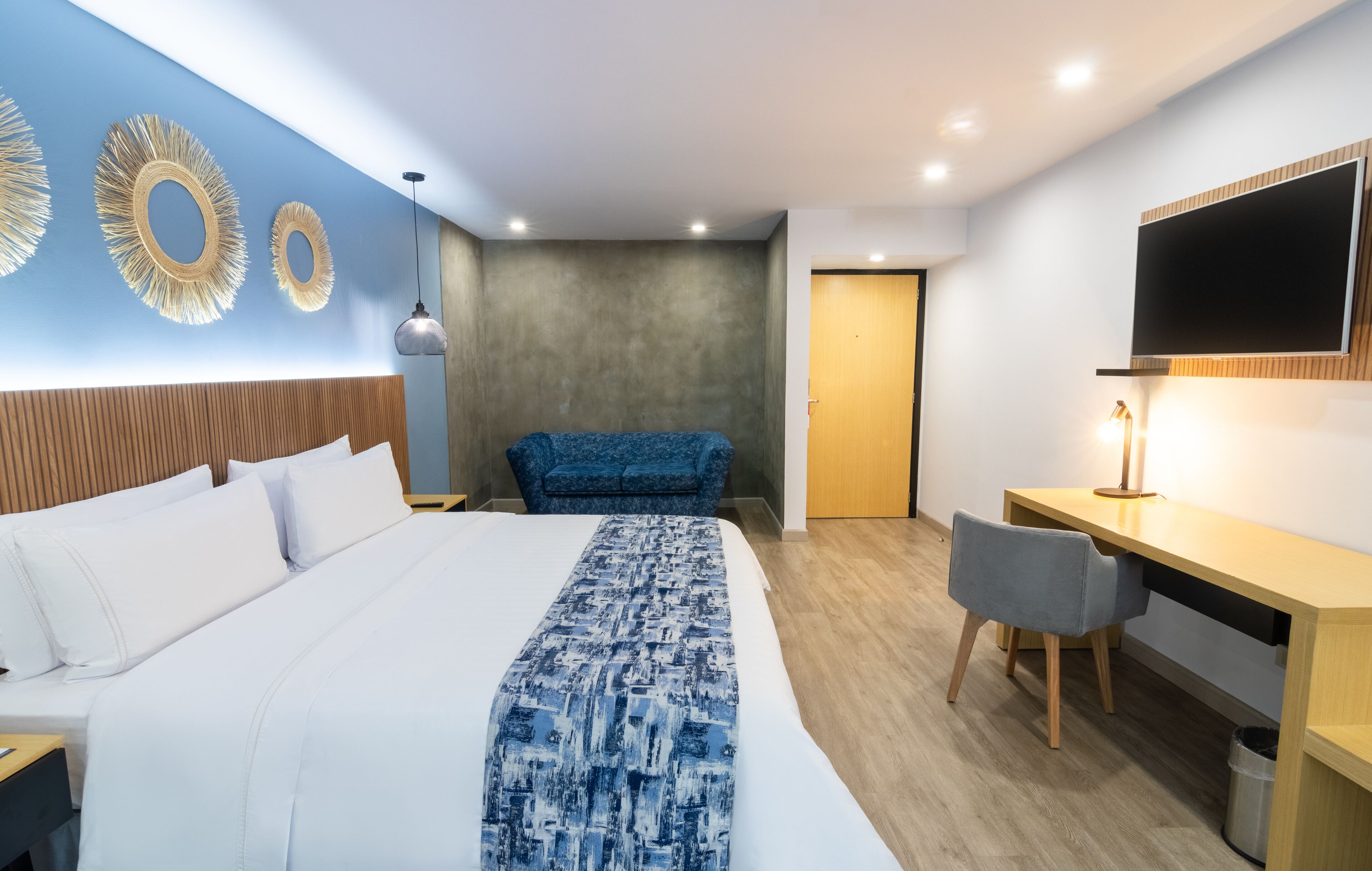 Une chambre d’hôtel moderne, dotée d’un grand lit, d’un bureau et d’une télévision.