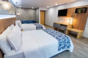 Une chambre d’hôtel moderne équipée de deux lits, d’un bureau, d’une télévision et d’une petite plante.