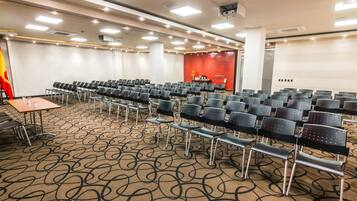 A conference room with rows of chairs, a table, and a red accent wall.