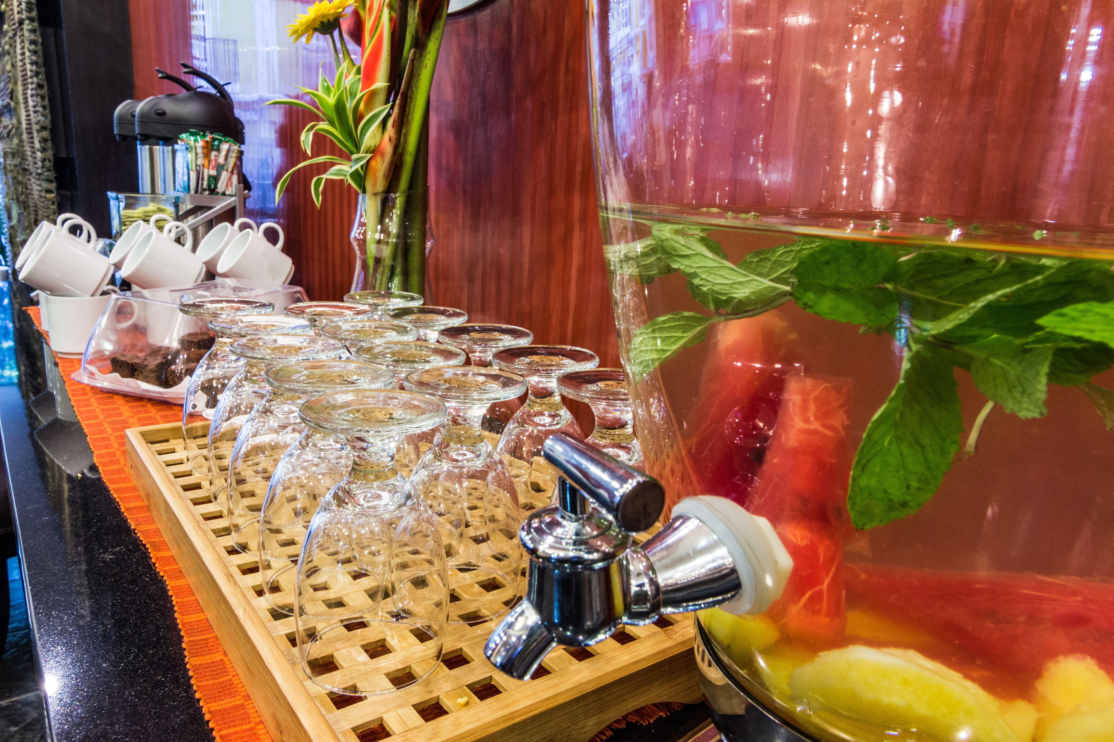 A bar area with a variety of glasses and a large pitcher with fruits and mint leaves.