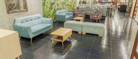 A hotel lobby with seating areas, a reception desk, and a mural on the wall.