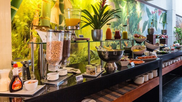 Een buffet met diverse gerechten en sauzen, een koffieapparaat en een grote plant.