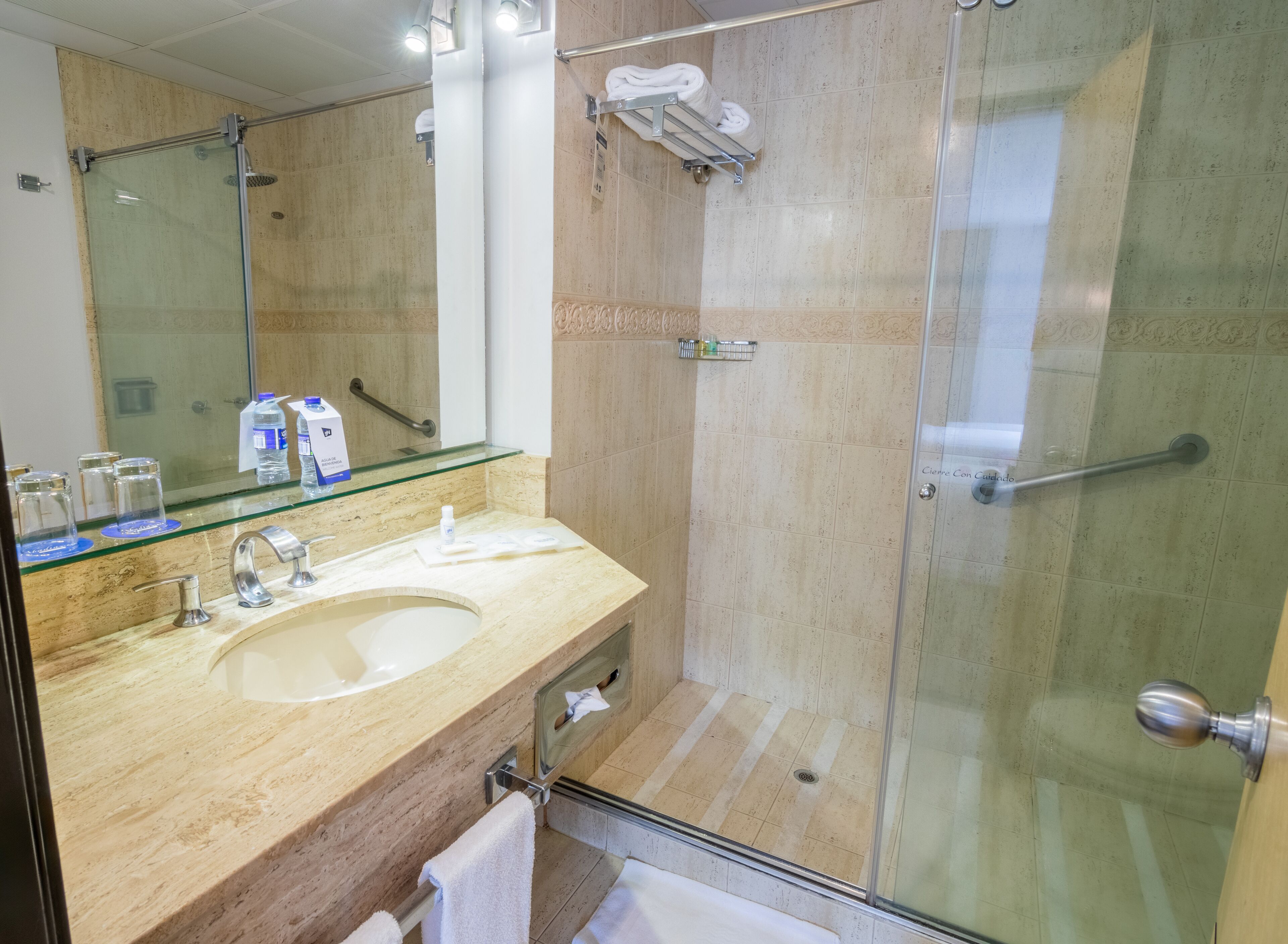 Ein modernes Badezimmer mit Duschkabine aus Glas, Marmorwaschbecken und einem Waschtisch mit Glasplatte.