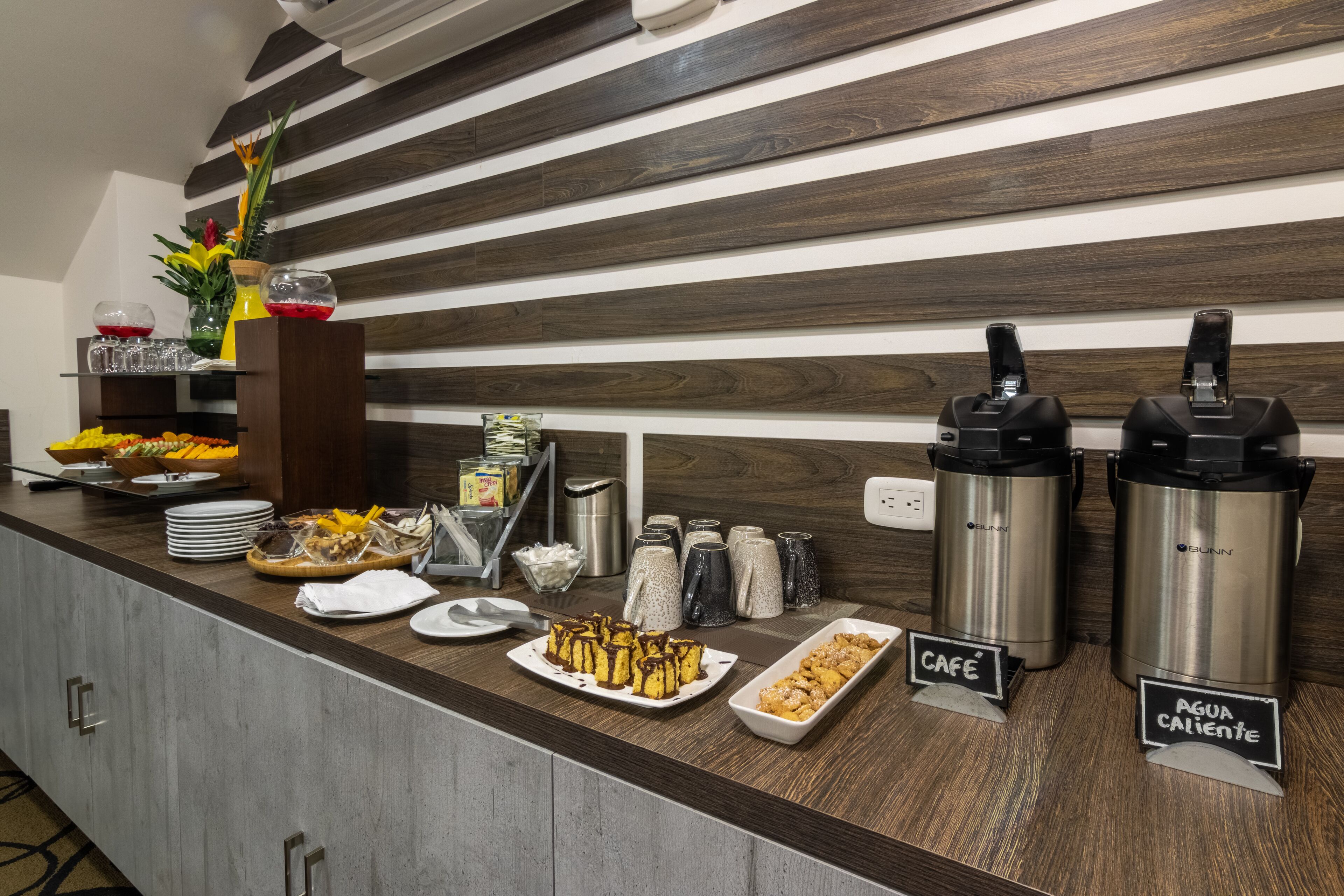 A buffet setup with various food items, coffee and tea dispensers, and labeled beverage options.