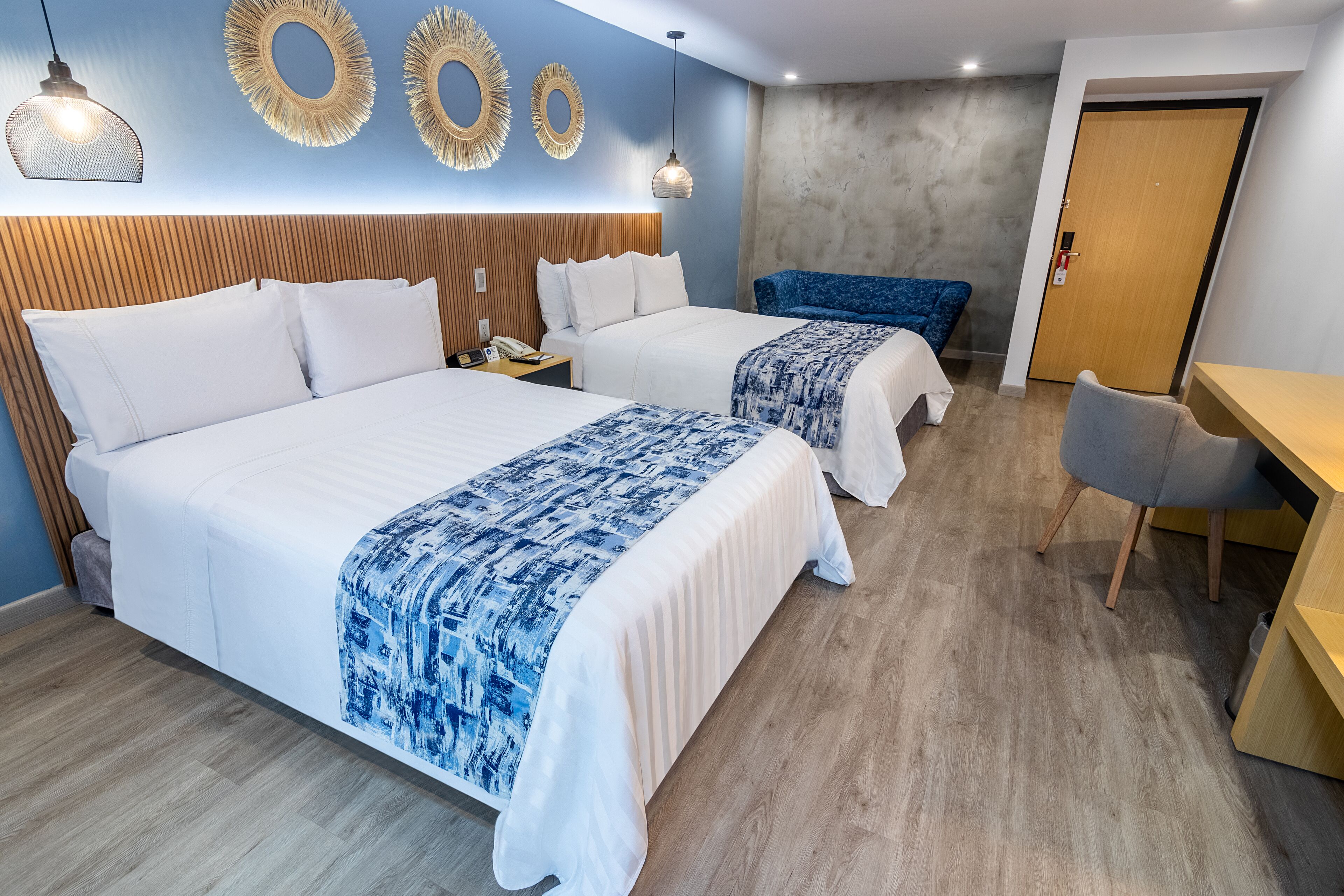 A hotel room with two beds, a desk, and a chair.
