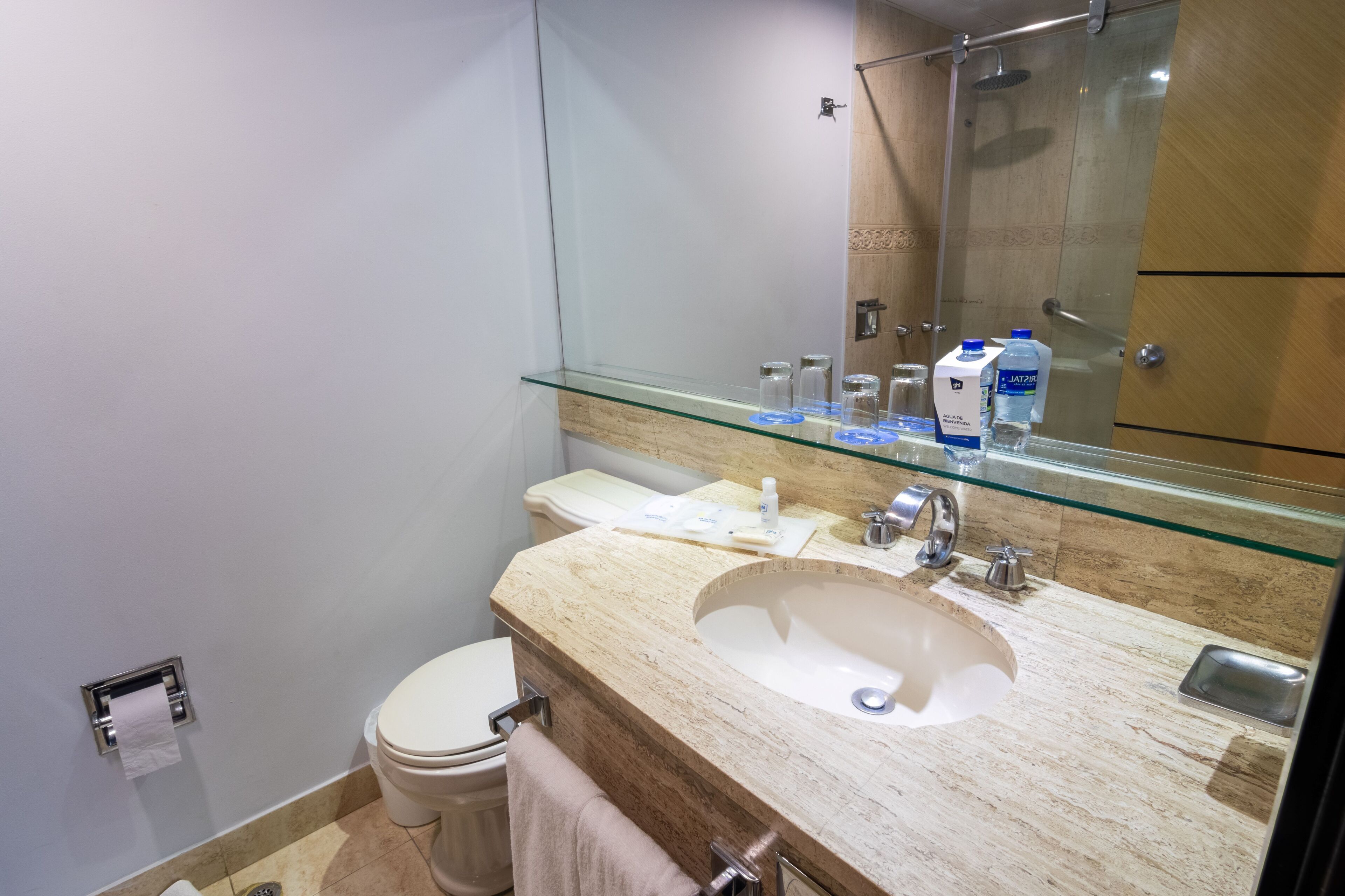 A modern bathroom with a glass-enclosed sink, a toilet, and a shower.
