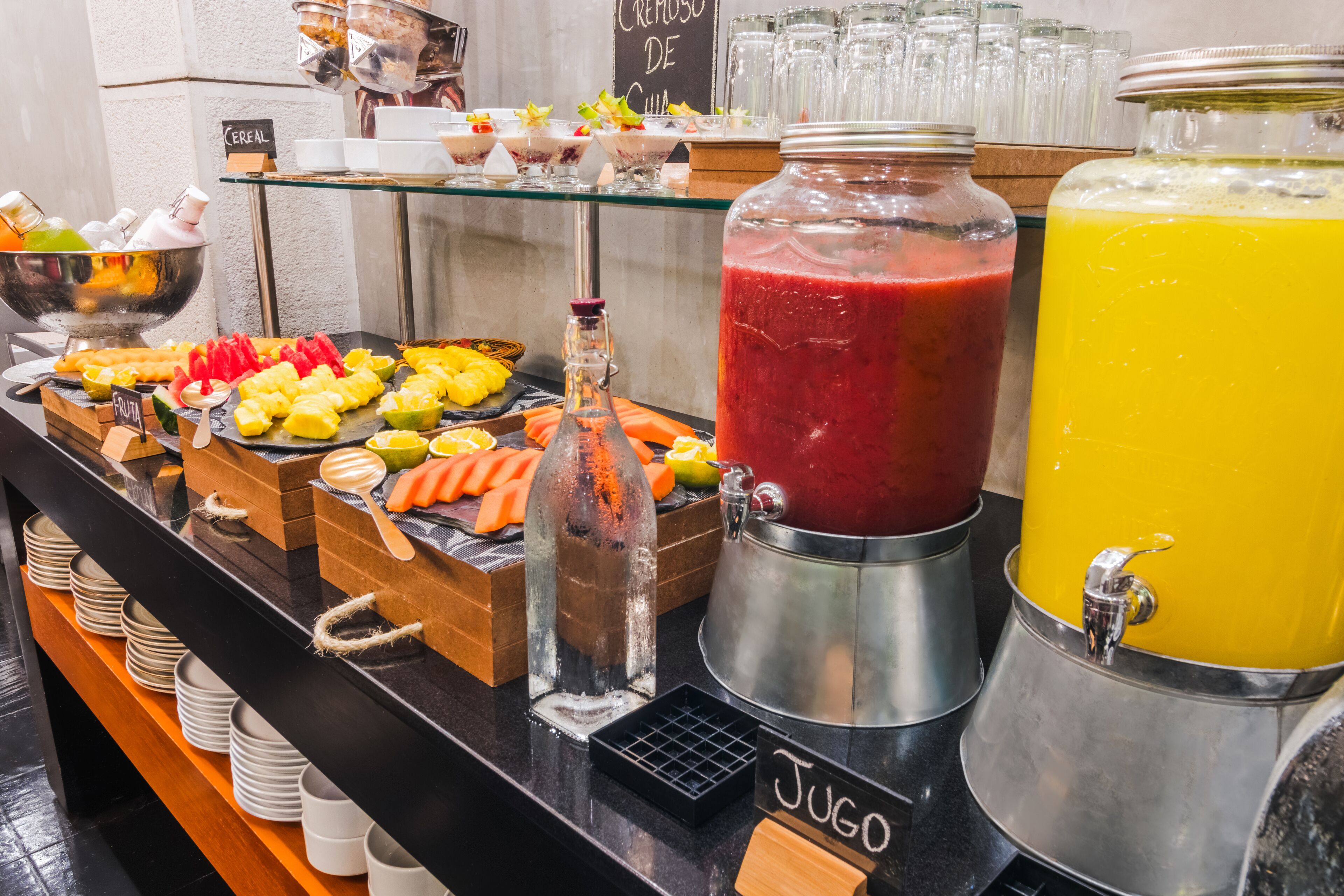 A buffet with various food items and beverages, including a fruit section, a juice bar, and a cereal display.