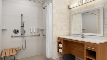 Un baño moderno con ducha, un banco de madera, un tocador con espejo y azulejos con diseño.