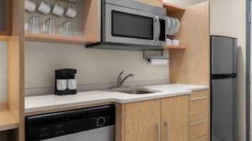 A modern kitchen with a built-in microwave, coffee maker, dishwasher, and refrigerator.