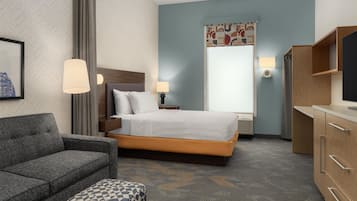 Una habitación de hotel con cama, sofá, televisor y escritorio.