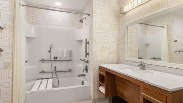 A modern bathroom with a bathtub, shower, vanity, and a large mirror.