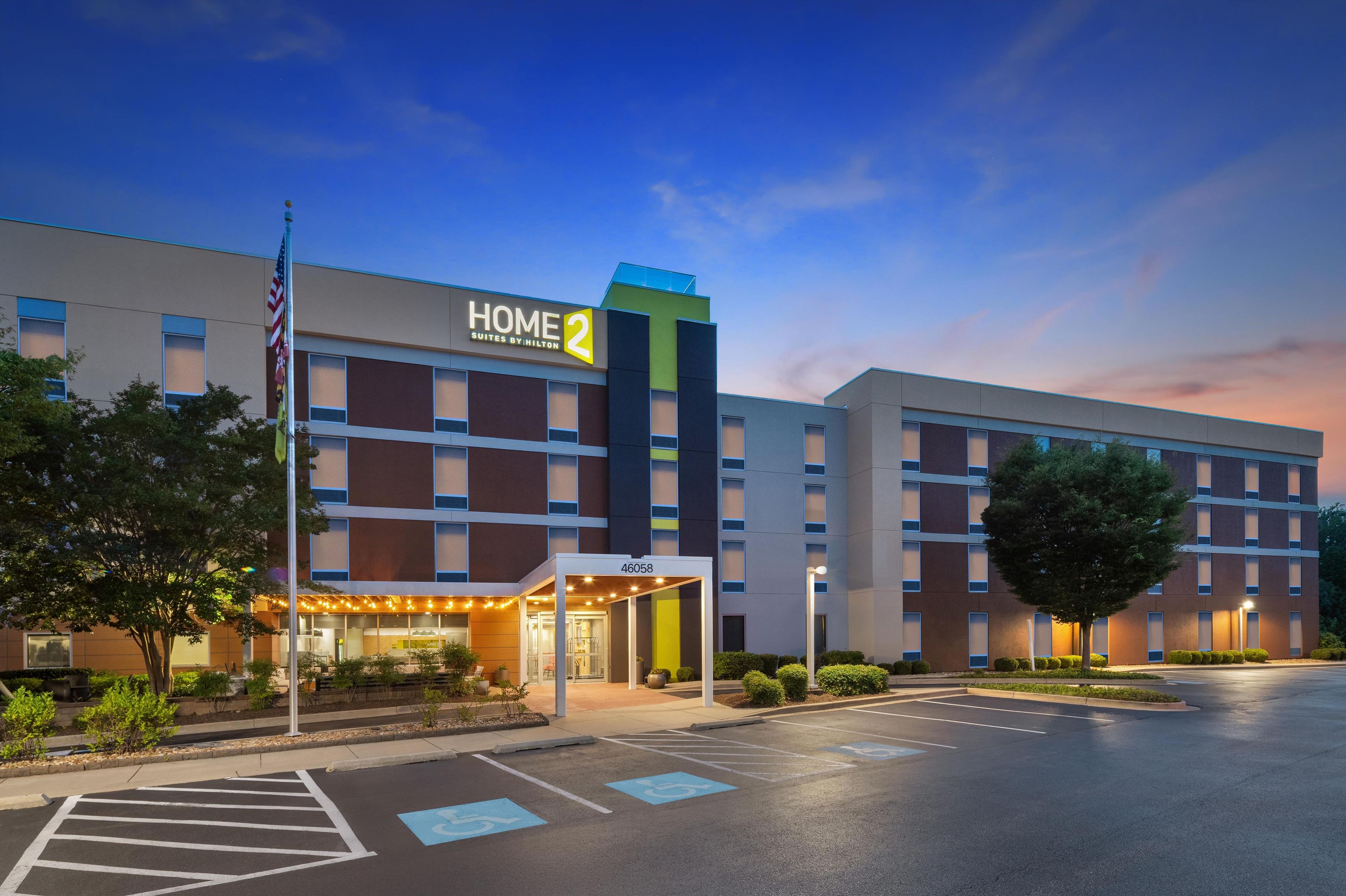 A hotel with a modern design, featuring a prominent 'HOME 2' sign, a covered entrance, and a parking lot.