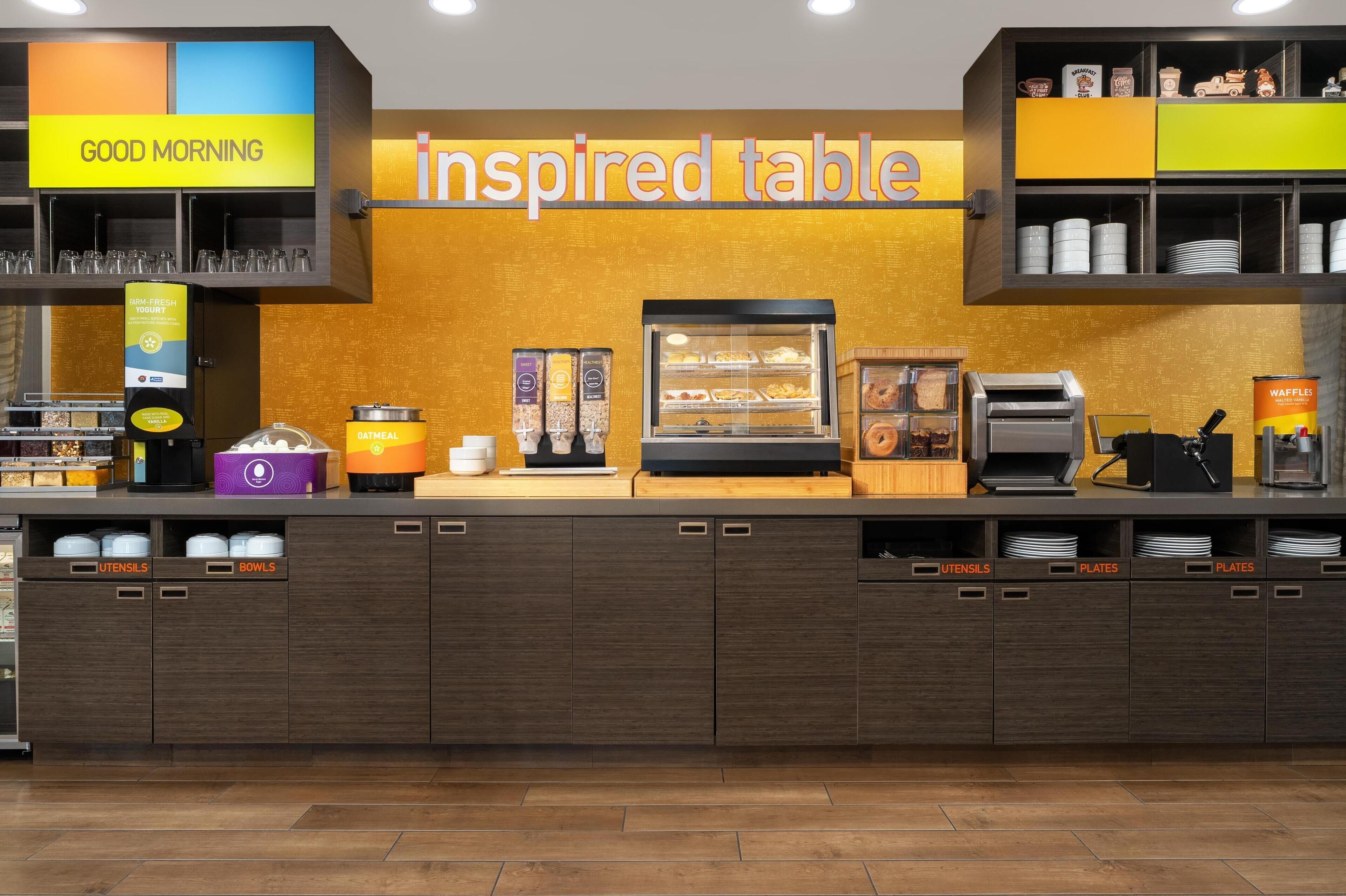 Una colazione a buffet con un cartello che dice 'Good Morning', un cartello che dice 'Inspired Table', e diversi cibi e utensili.