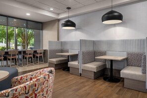 A modern restaurant with booth seating, pendant lighting, and a view of the outdoors. - Home2 Suites by Hilton Lexington Park Patuxent River NAS, MD (Lexington Park)