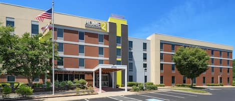 A modern hotel with a "Home 2" sign, a covered entrance, and a parking lot with handicapped parking spaces.