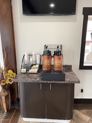 Enjoy a convenient coffee station with a coffee machine, dispensers, and cups, perfect for a quick morning start.