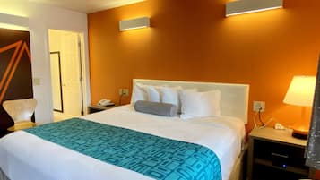 Une chambre d’hôtel avec un grand lit, une table de chevet, une lampe et un luminaire fixé au mur.