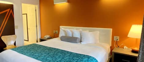 Habitación de hotel con una cama grande, una mesita de noche, una lámpara y una lámpara de pared.