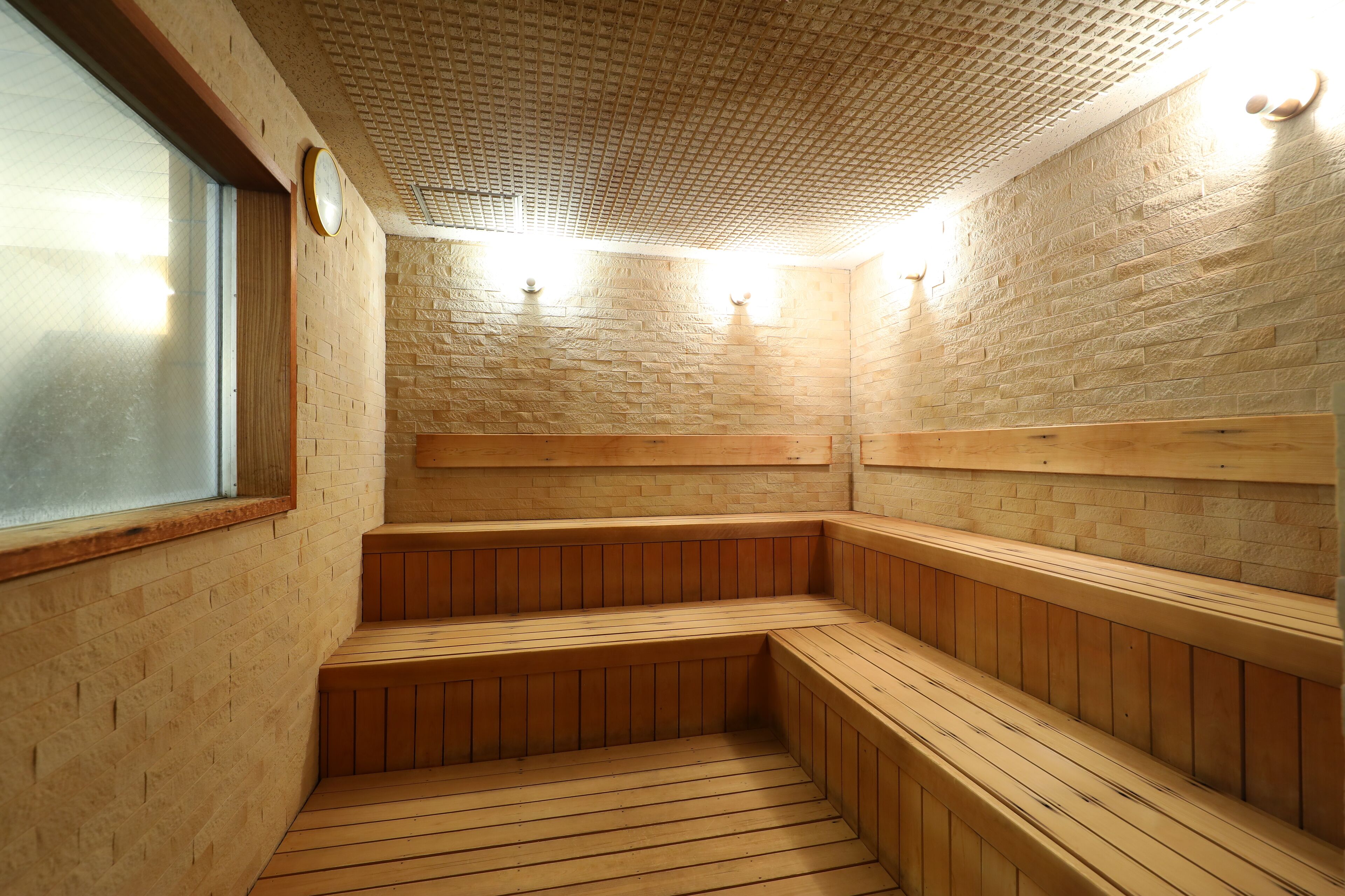 A sauna with wooden benches and a brick wall.