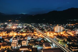 A nighttime cityscape with illuminated buildings and a prominent highway.