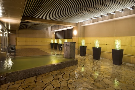 A spa area with a stone floor, a small pool, and several planters with plants.