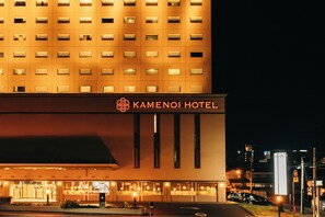 A hotel with a modern facade, illuminated windows, and a prominent hotel sign.