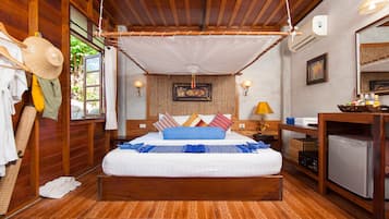 Cozy retreat with a large bed, wooden desk, and a window offering a view of lush greenery.